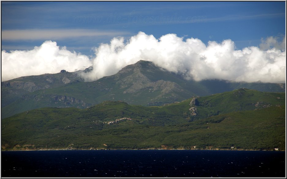 AIDA136.jpg - Am späten Vormittag fahren wir um Korsika herum und steuern französische Gewässer an. Wir passieren das Cap Corse im Norden Korsikas und ich geniesse das herrliche Panorama. Hinter der Steilküste liegen Felder und Weinberge und gleich dahinter beginnt ein Gebirge mit schneebedeckten Gipfeln.