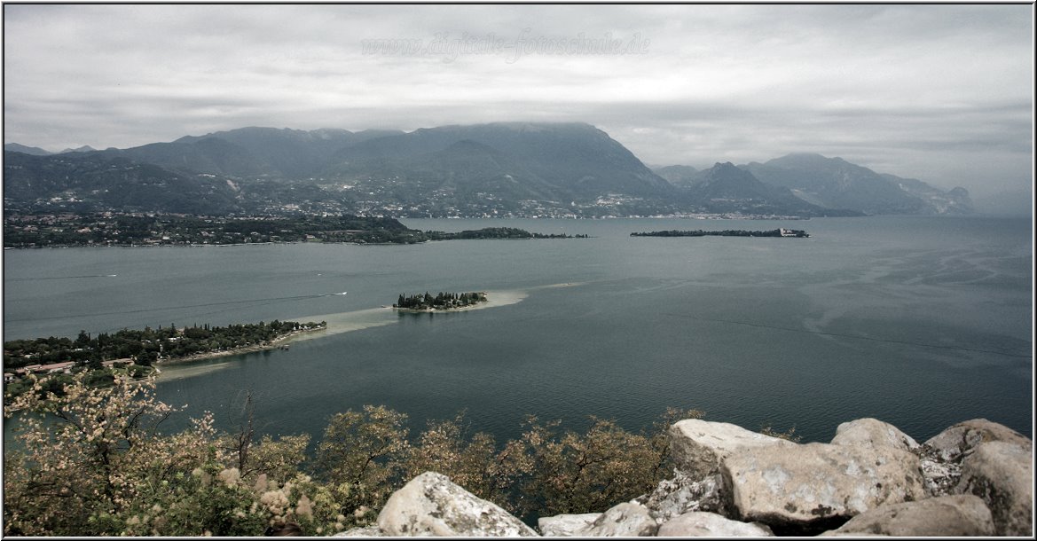 Manerba_006.jpg - Nördlich der Rocca di Manerba läuft die schmale lange Landzunge Punta Belvedere in den See. Sie kann man gut vom Aussichtspunkt sehen. Von deren Spitze kann man zur Zypresseninsel San Biagio hinüberwaten, die an ihrem seichten Ufer herrliche Badestellen bietet; darum heisst sie wohl auch: die Badeinsel. Wir sind nicht bis da runter gegangen, sondern vom Rocca weiter nach Saló gefahren.