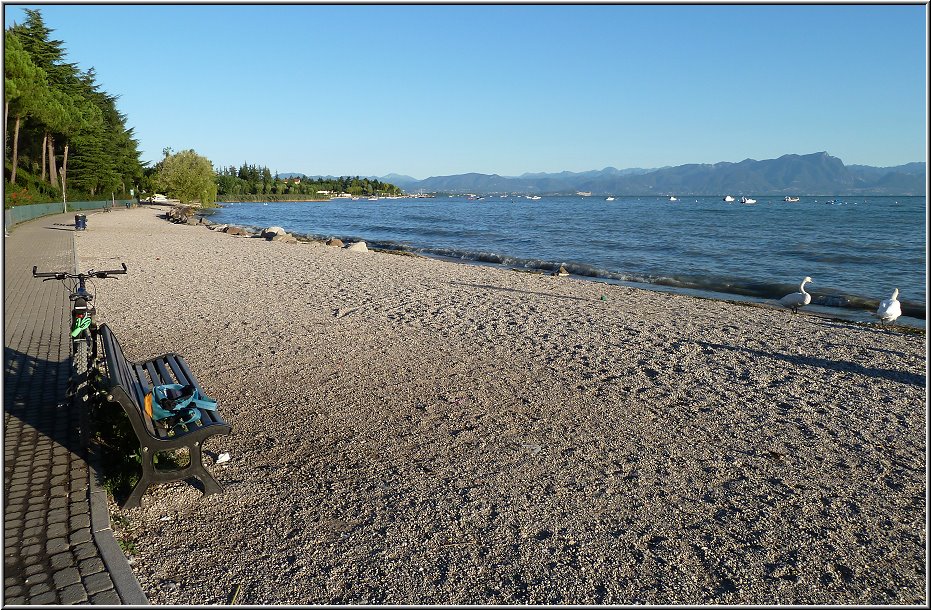 Peschiera_039.jpg - Mit dem Mountainbike unterwegs nach Sirmione. Hier siehst Du auch die typische Uferbeschaffenheit: Stein, Kiesstrand, Uferpromenade, Campingplatz und an manchen Stellen stattdessen Restaurants und Lokale. Bademöglichkeiten gibt es an beiden Seiten des Ortes, nördlich in Richtung Lazise und südwestlich auf dem Weg nach Sirmione. Am flachen Ufer zwischen Peschiera und Sirmione gibt es ein paar gute Bademöglichkeiten und zahlreiche Campingplätze mit großen Wiesenflächen, die bis an den See reichen. Diese Abschnitte sind deutlich schöner und etwas breiter, als die Strände in Richtung Lazise.