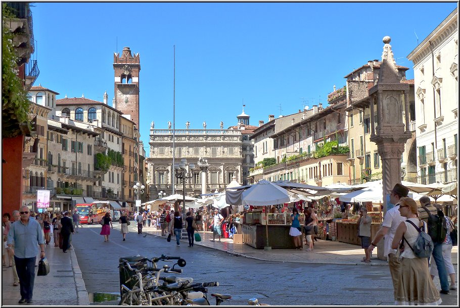 Verona_011.jpg - Von der Arena geht unsere Verona- Entdeckungsreise weiter durch die schöne, aber leider recht volle Altstadt zum Piazza delle Erbe. Die Via Mazzini, die dort hinführt, gilt als die eleganteste Einkaufsstrasse Veronas. Das kann ich bestätigen, wenn mir auch bei so manchen Preisen in den Schaufenstern schwindelig wurde. Auf dem Piazza delle Erbe brummt Verona, Tausende von Menschen laufen kreuz und quer, unzählige Marktstände stehen herum und ich achte erst im zweiten Blick auf den berühmten Marmor-Baldachin (Capitello). Der hohe Wehrturm Torre dei Lamberti überragt hier alles.