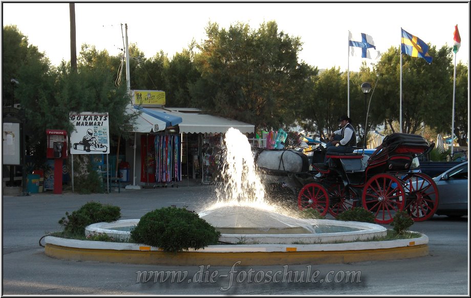 Tigaki_Tingaki_Fotoschule_048.jpg - Der Stadtmittelpunkt von Tigaki, Romantiker können eine Kutschfahrt mieten. Einmal die Straße rauf und wieder runter für 15 Euro. Ein skurilles Bild zwischen den knatternden Rollern.